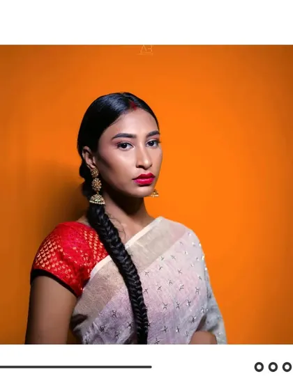A clean, striking studio portrait. The bold orange background contrasts beautifully with the model's traditional attire, creating a modern and graphic image.