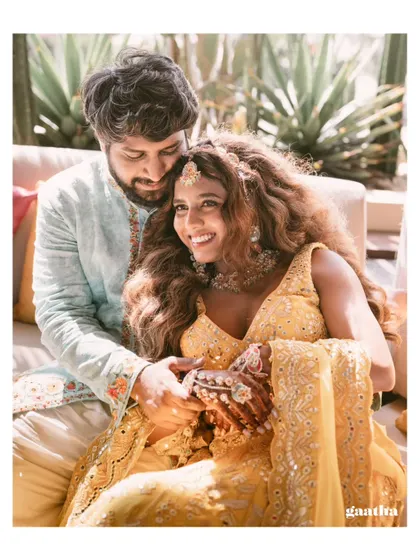 An intimate and happy moment between the couple at their vibrant Bali Haldi, surrounded by lush greenery and custom decor.