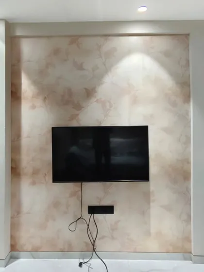 A soft, watercolor-style floral wallpaper used as a backdrop for a TV wall. The subtle pattern adds texture without distracting from the screen.