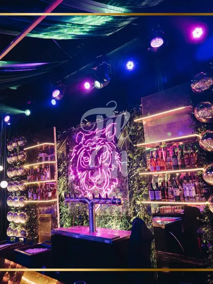 The bar was a major focal point, featuring a magnificent 24-foot structure with a striking neon tiger portrait. Gold shelving and playful monkey figures holding light bulbs added to the whimsical yet sophisticated feel of this tropical-themed Sangeet bar design.