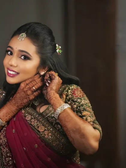 A candid moment of Dr. Saruna adjusting her earring. This shot captures her elegance and the beautiful details of her reception look.