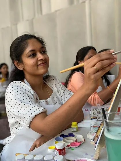 A participant smiles as she adds details to her sunset painting. Seeing people find joy and confidence in their creativity is the best part of my job.