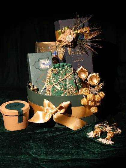 A luxurious corporate gift hamper for DC Group, featuring a bottle of premium whiskey, a silk potli bag, and other elegant items in a rich green and gold theme.