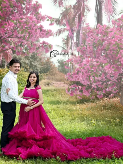 A fairytale-like portrait of a couple in a pink-themed outdoor setting. The long, flowing ruffled gown is the centerpiece of this magical shot.
