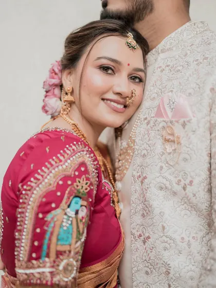 An intimate close-up of the bride on her wedding day. This shot highlights the detailed embroidery on her blouse, her soft and glowing makeup, and the serene expression on her face.