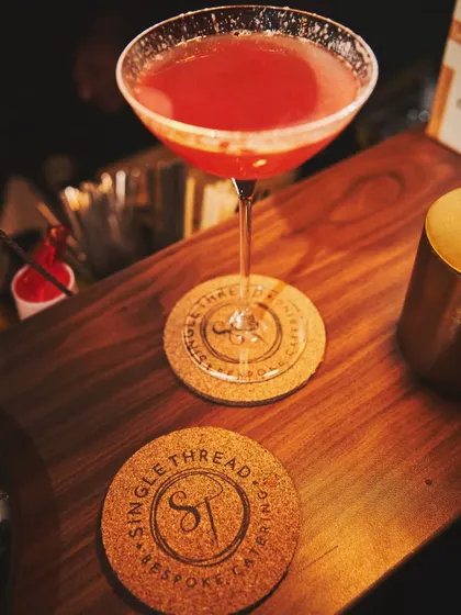 A cocktail resting on a custom 'Single Thread' coaster, another small branding detail that enhances the overall experience.
