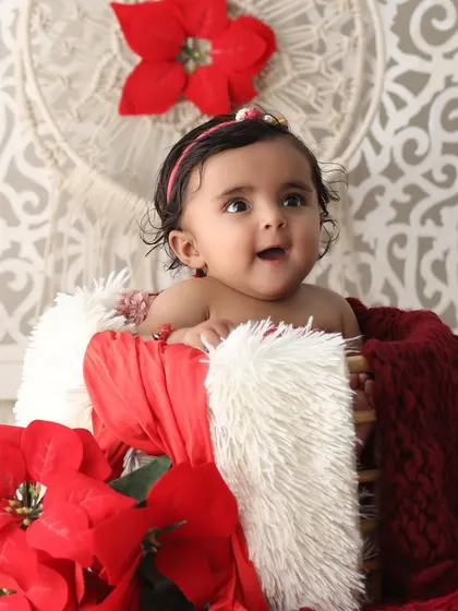 A happy and bright-eyed five-month-old baby girl. Her joyful expression is the centerpiece of this photo, taken in a festive and colorful studio setting.