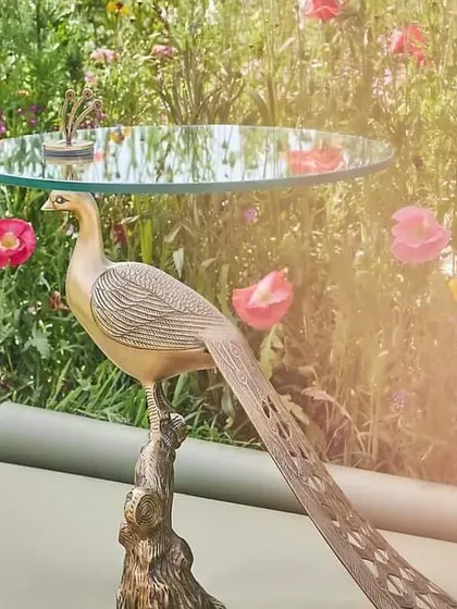 A truly unique handcrafted side table featuring a peacock base made of aluminum with a detailed finish, topped with 8mm toughened glass.