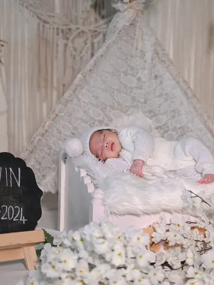 A classic all-white newborn setup. This clean and timeless look includes a small bed, soft blankets, and a personalized slate to announce your baby's name and birth date, creating a beautiful keepsake.