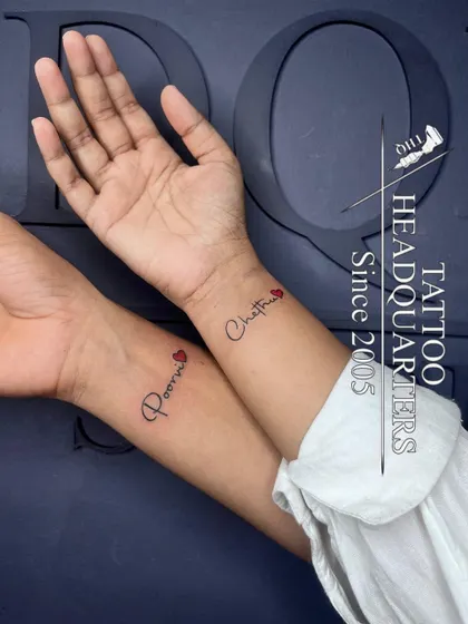 A matching couple's tattoo, with the names "Poorni" and "Chathu" inked on their respective wrists, each adorned with a small red heart.