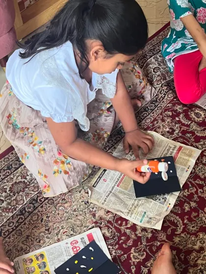 A child engrossed in the process of making her insect craft, carefully applying glue.