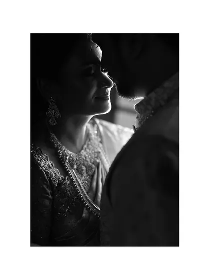 A beautifully lit black and white close-up, capturing the bride's gentle smile as she looks at her groom.