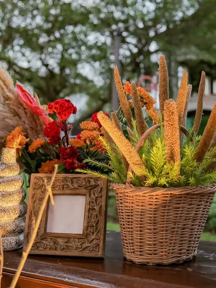 A close-up of a decorative vignette, featuring a basket of millet sprays and a rustic carved photo frame.