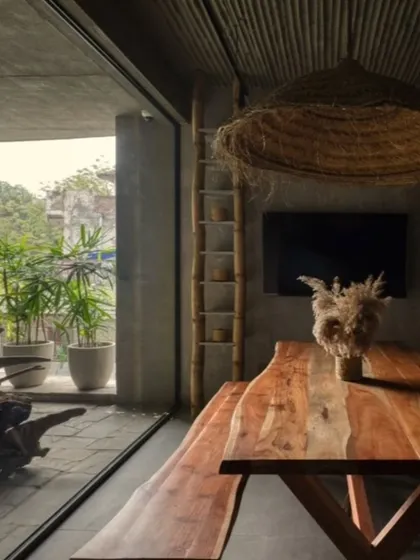 This dining area in my studio connects directly to an outdoor patio, blending rustic and modern aesthetics. The live-edge wooden table, bamboo ceiling, and raw concrete walls are all part of my philosophy of using natural, earthy materials to create spaces that feel grounded and authentic.