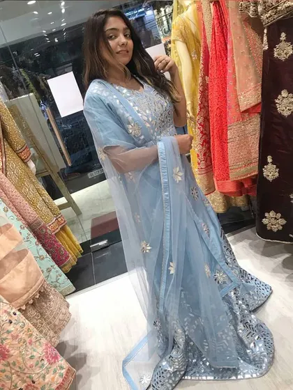 A client trying on a powder blue Anarkali gown with silver mirror work in my store. This is a great way to see how the outfit fits and feels before you rent it.