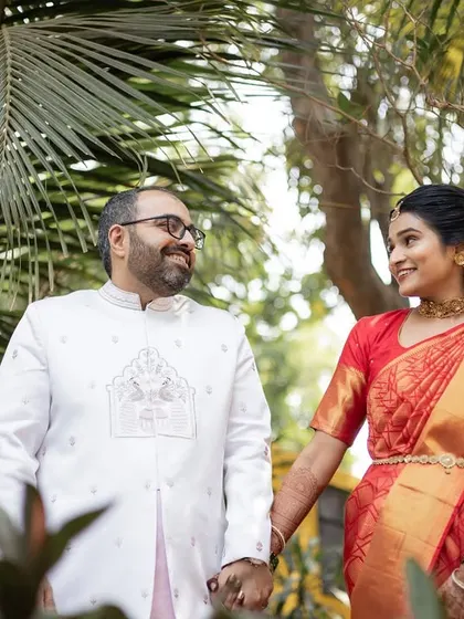 A happy couple holding hands and walking through a garden. A simple, sweet, and natural portrait.
