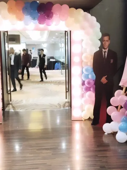 Guests walking through the lit balloon archway. This view shows how the entrance serves as a perfect transitional piece from the reception area into the main event hall.