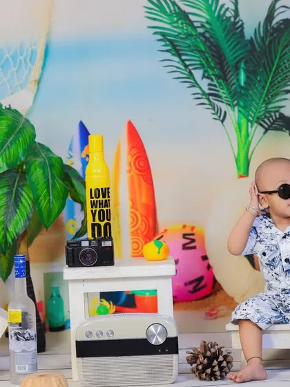 A baby boy looking very cool in sunglasses, chilling on a miniature beach chair in our vibrant and fun beach setup.