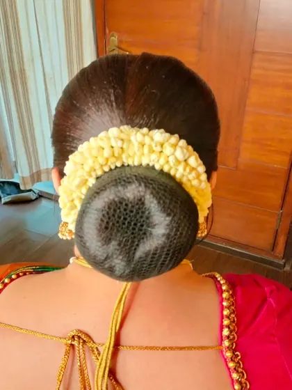 A sleek, polished bun with a net cover, wrapped with a traditional jasmine gajra.