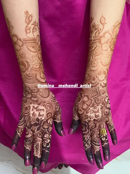 A full view of the "Mom to be" and "Dad to be" mehendi design, showing how the patterns extend elegantly up the forearms.
