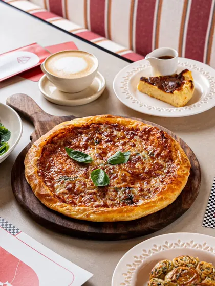 A classic cafe scene featuring a pizza, a slice of Basque cheesecake, and a coffee. This shows our ability to create a complete table setting that feels authentic.