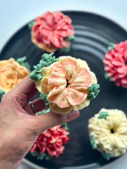 A soft-hued peach and yellow floral cupcake, perfect for a spring or summer theme.