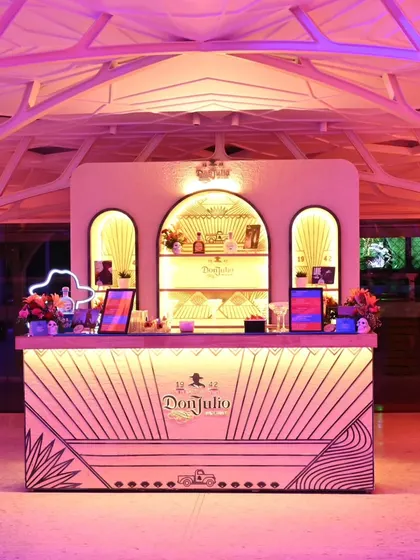 The Don Julio bar under dramatic pink lighting, showcasing its striking design and how it transforms into a vibrant centerpiece for an evening party.