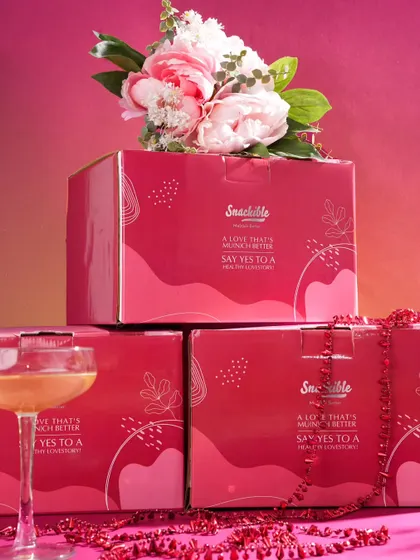 This shot focuses on the special edition Valentine's packaging. Stacking the boxes and styling them with flowers and a cocktail glass creates an elegant and celebratory image, perfect for promoting a limited-time offer.