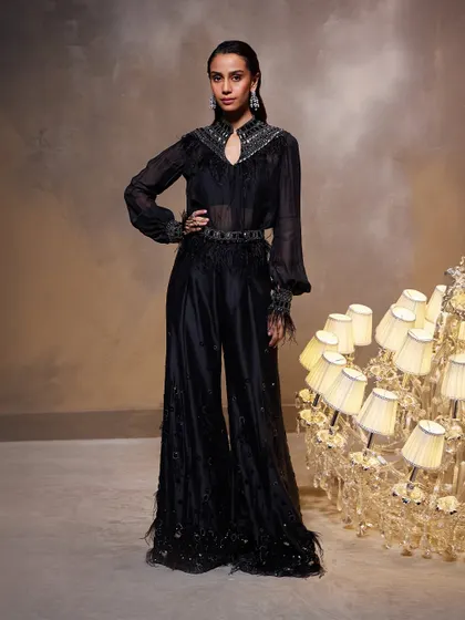 The Amore Pant Set is a whimsical masterpiece designed for a dramatic fusion wear statement. This all-black ensemble glimmers with our signature stone embellishments and is finished with delicate feather-like details on the sheer top, cuffs, and pants.