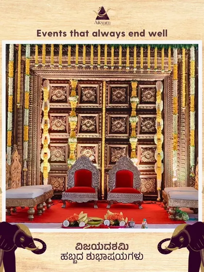 A festive stage setup for a Dasara celebration. The decor features traditional carved panels, royal silver chairs, and elegant floral arrangements, creating a perfect backdrop for the occasion.