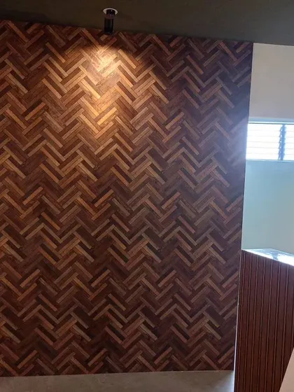 A dark wood-effect wallpaper with a herringbone pattern, creating a warm and sophisticated accent wall.