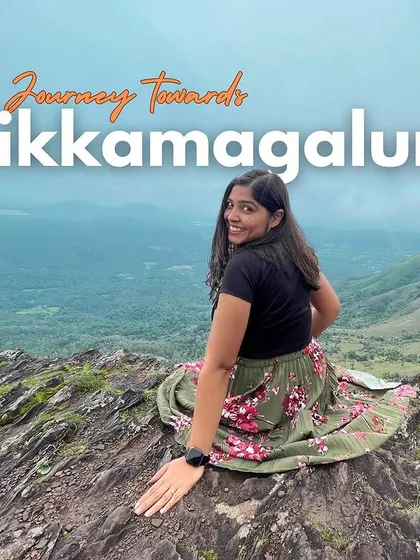 The journey towards Chikmagalur is filled with stunning views. Here, a traveler sits on a rocky ledge, taking in the panoramic beauty of the region.