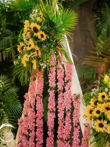 A close-up of the floral backdrop, where I combined strings of pink flowers with bunches of sunflowers and palm leaves to add a pop of contrasting color and a tropical touch.