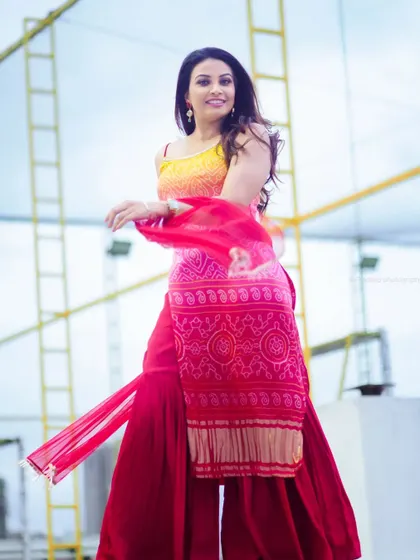 An outdoor shot in a colorful sharara suit. The rooftop setting and the model's joyful movement create a lively and celebratory feel.