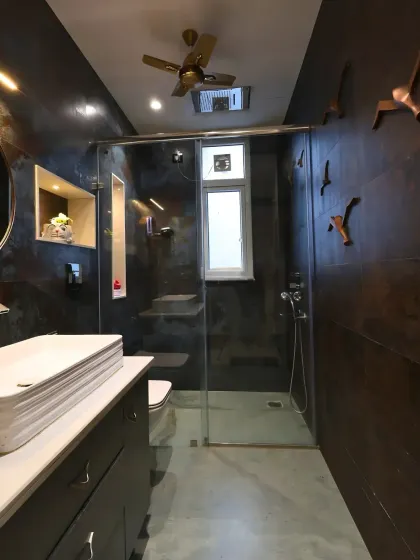 A sleek PU finish vanity with modern sanitary ware and a round copper-framed mirror adds playful elegance to the space.