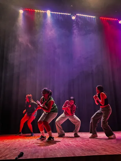 Dancers in formation under the stage lights, a moment of focus and unity before the choreography explodes with energy.