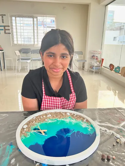 A young artist with her finished beach resin art, complete with a tiny boat.
