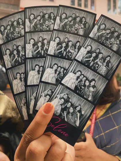 A close-up of a hand holding a fan of black and white photo strips with a custom pink "Selene" logo.