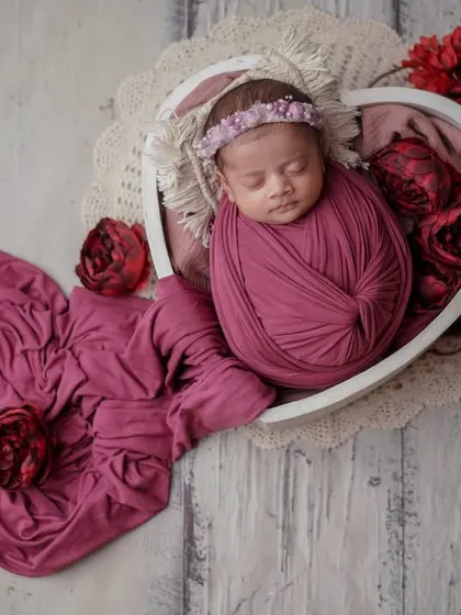 A little bundle, wrapped in wonder. The heart-shaped bowl and flowing fabric create a beautiful, romantic scene for this sleeping, swaddled baby.