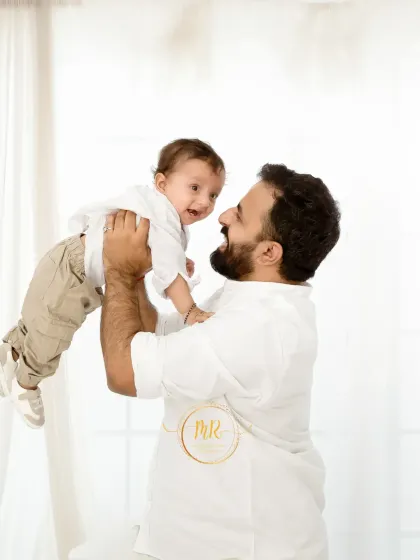 A joyful father lifts his baby high in the air. This dynamic shot, part of a light and airy session, perfectly captures the fun and energy of family life.