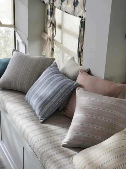 A close-up of the striped fabric on the window seat cushions. The soft, natural light from the window beautifully illuminates the texture and subtle colors of the textile.