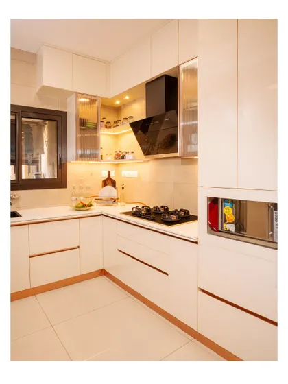 A pristine all-white modular kitchen with glossy finishes and rose gold accents. The design is elegant, timeless, and makes the space feel bright and spacious.