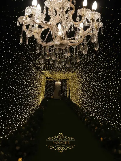 We transform spaces into magical realms. This tunnel of countless fairy lights, leading to a grand chandelier, creates an enchanting entrance for a glamorous cocktail night, promising an evening of wonder.