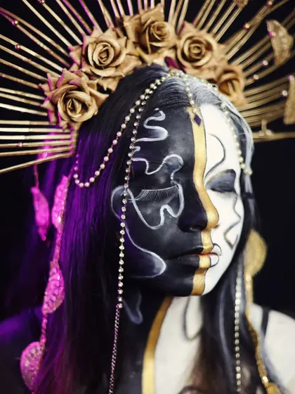 A high-contrast, black and white fantasy look with gold accents and an elaborate headpiece.