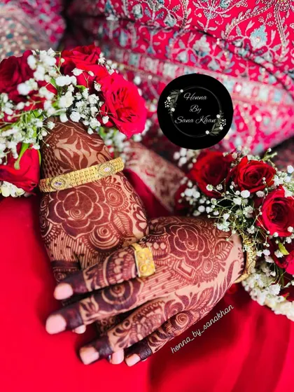 The rich, reddish-brown stain of a floral design, beautifully captured with the bride's jewelry and red outfit.