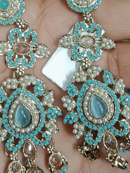 These turquoise-coloured earrings are perfect for adding a pop of colour to your outfit. The design is intricate, with small pearls and Polki stones adding to their charm.
