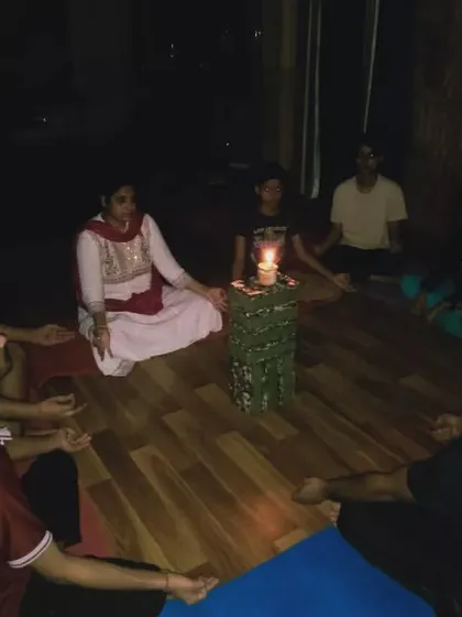 Students sit in a circle around a central flame for a Trataka session. This ancient practice is a journey from external focus to internal awareness, leading to mental clarity and peace.