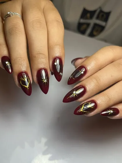 A little bit of magic. This deep maroon stiletto set is adorned with gold celestial charms and sparkling rhinestones.