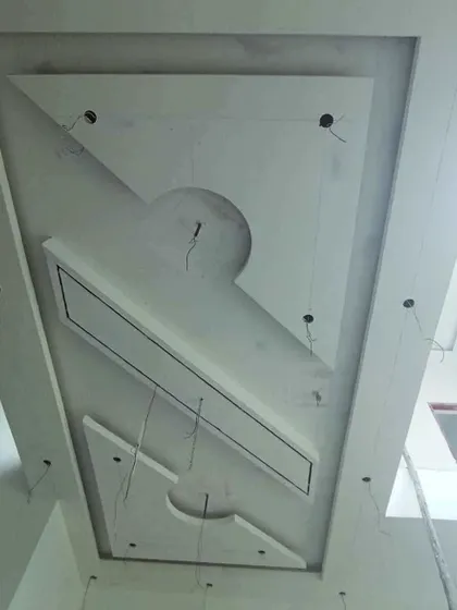 A modern, asymmetrical gypsum ceiling design with rectangular and semi-circular elements, shown with wiring ready for lights.