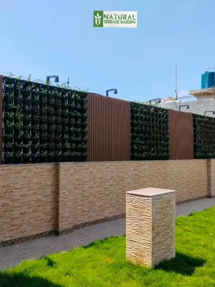 A long boundary wall featuring alternating sections of vertical gardens and WPC panels.